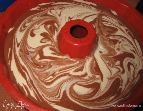 В форму для выпечки налить 4 ложки белого теста , затем  4 ложки темного и так чередовать до окончания теста Вилкой перемешать слегка плавными круговыми движениями