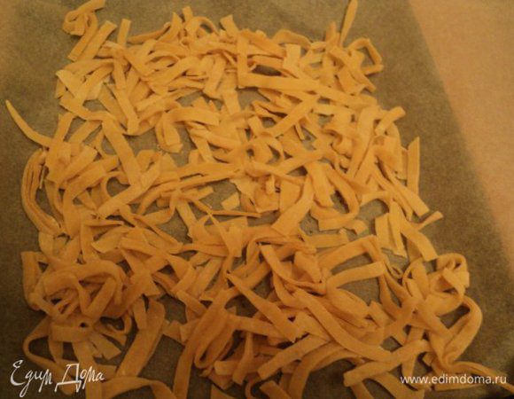 Затем раскатать тесто в тонкий пласт и дать ему подсохнуть. Порезать пласт полосами шириной  4-5см, сложить друг на друга и нарезать лапшу шириной 4-5мм. Выложить лапшу тонким слоем на слегка подсыпанный мукой пергамент и дать подсохнуть.