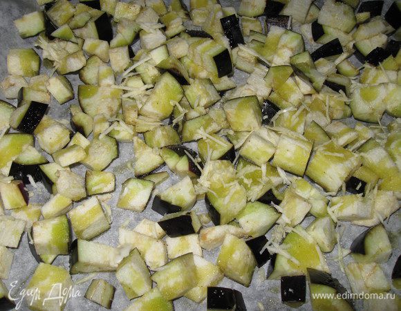 Баклажан режем кубиком, кладем на протвень, застеленный пекарской бумагой, сбрызгиваем оливковым маслом, посыпаем крупной солья и крошим 2-3 зубчика чеснока