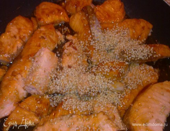 Порезать лосось на кусочки и обжарить на оливковом масле. На сухую сковородку налить соус терияки и переложить на нее рыбку, сверху также залить соусом и посыпать кунжутом. Подержать под крышкой на слабом огне 5 минут.