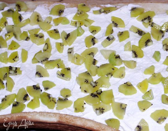 Сначала пропитываем его ликёром,потом промазываем кремом и посыпаем киви.