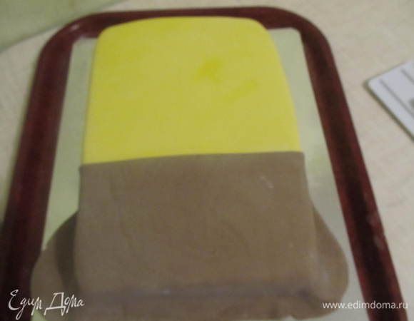 После того как тортик хорошо выровняли можно приступать и к украшению. Раскатать желтую мастику и накрыть им половину тортика (желательно больше половины). Вторую половину (поменьше) покрыть коричневой мастикой. Чтобы место стыка 2-х цветов было ровное, перед покрытием с одного края, надо отрезать ровненькую линию.