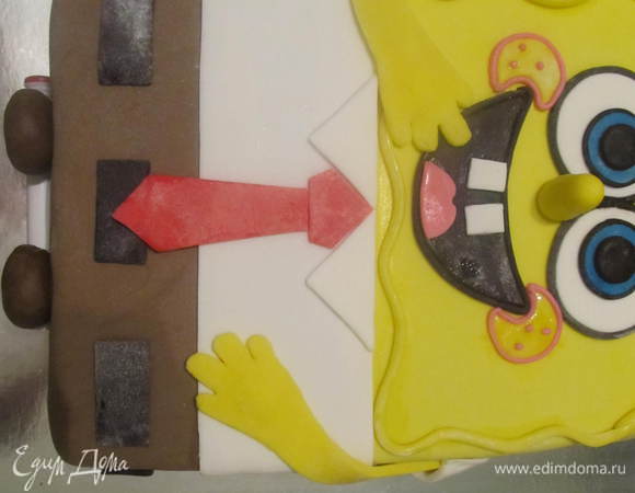 Из черной мастики делаем ремень, не забываем и про бока тортика (всего 5 полосочек). Из красной вырезаем галстук. Из коричневой мастики скатать 2 небольших колобка, немного прижать к столу, чтобы были немного плосковатые и прекрепить их на бок торта где будут ножки. Пока штанины пристанут к торту, можна под низ что-то подложить чтобы не падали. Потом в серединку их прекрепить наши ножки с туфельками.