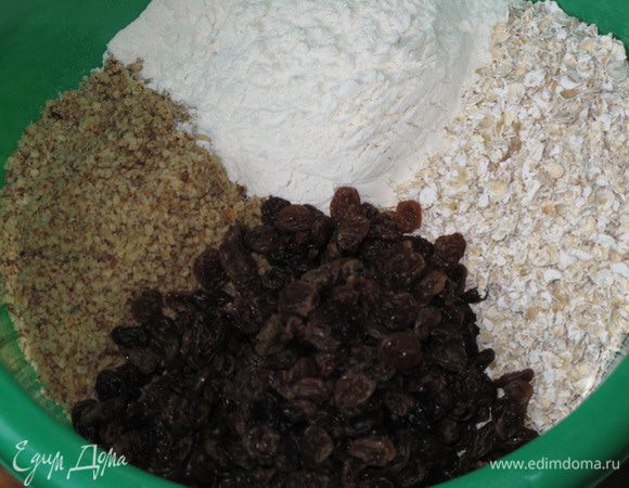 Отдельно перемешайте овсяные хлопья (я беру Геркулес №2 - его не надо измельчать) с мукой, орехами, изюмом и содой.