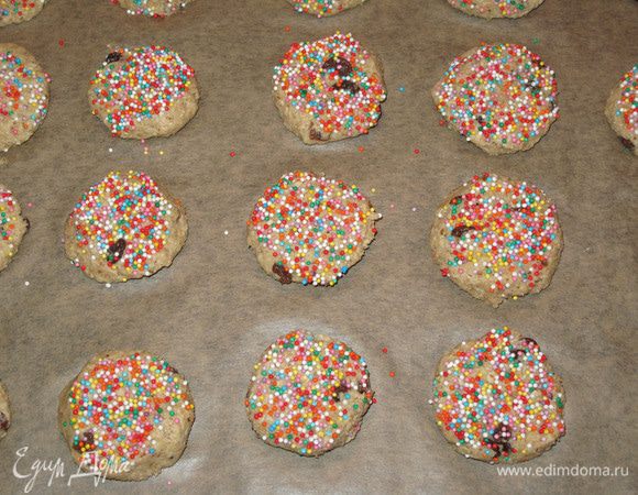 Сформируйте из теста шарики, (обмакните в разноцветную посыпку - это по желанию), положите их на противень, выстеленный пергаментом, и приплюсните руками.