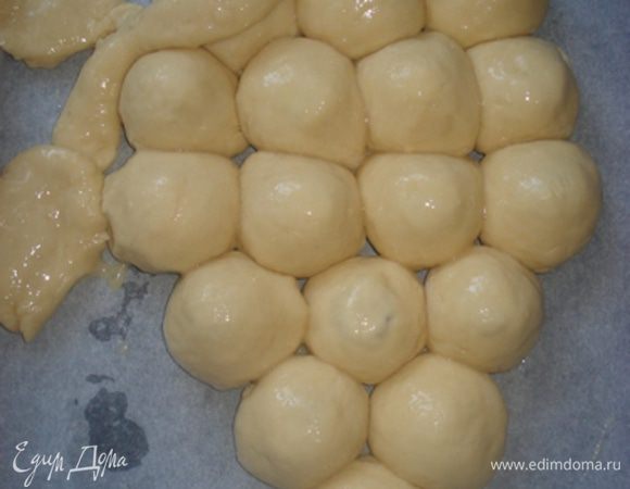Уложить шарики на противень в виде грозди винограда и смазать взбитым яйцом.
