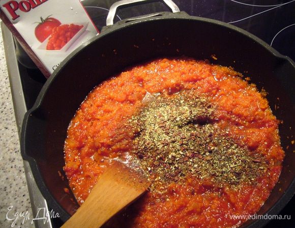 В это время готовим рагу. Лук и морковь мелко режем (я морковь измельчала в блендере). Оливковое масло хорошо прогреваем в глубоком сотейнике, обжариваем на среднем жару лук до прозрачности, добавляем морковь и продолжаем обжаривать 5 мин. Затем выкладываем томаты в собственном соку. 
Сразу добавила приправу "Песто с томатами и базиликом" и солёные перчики чили. Тушим овощи минут 15, потом добавляем горячий бульон и тушим ещё примерно 15-20 мин.  Через указанное время перец чили убираем, вливаем вино и продолжаем прогревать соус на малом жару 10 мин. 