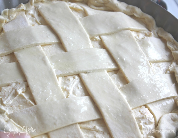 Разложить полоски решеткой на поверхности пирога, защипывая края. Сверху смазать яйцом.