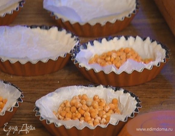 Из бумаги для выпечки вырезать круги по количеству и размеру тарталеток, выложить бумагу на тесто и насыпать сверху горох.