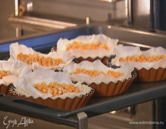 Отправить тарталетки в разогретую духовку и выпекать 10 минут с горохом, а затем 5 минут без гороха.