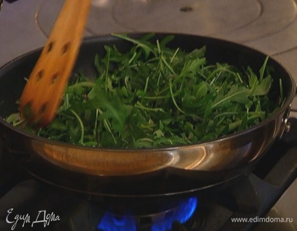 Не измельчая руколу, добавить ее в сковороду, перемешать с луком и прогревать все вместе около минуты, затем снять с огня.
