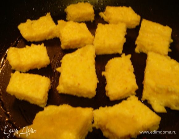 Разогреваем пару столовых ложек оливкового масла на чистой сковороде и обжариваем кубики поленты до слегка золотистого цвета минуты по 3-5 с каждой стороны. Рекомендую ее все же переворачивать осторожно, у меня она в этот раз немного хрупкая получилась, а в предыдущие разы была крепче.
Поленту солим и перчим по вкусу, выкладываем на бумажное полотенце, чтобы стек лишний жир. На этом этапе ее можно посыпать базиликом, я же его добавляла в самом конце. Накрываем поленту фольгой или крышкой, чтобы она оставалась теплой