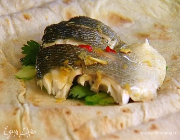 Лаваш разделить на части, выложить на каждую немного нарезанного огурца, кусок запеченной рыбы и пару веточек кинзы. Свернуть конвертиками.
