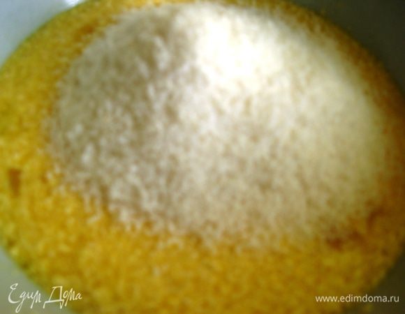 Тесто делим на 2 равных части. В одну добавляем кокосовую стружку, просеянную муку и разрыхлитель. 