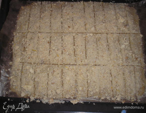 Смазать тесто слегка взбитым белком. Равномерно посыпать оставшимися крошками теста. Разрезать на полосы примерно 2х10см.