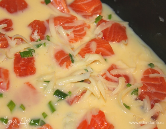 Форму для омлета смазать кусочком сливочного масла. Выложить семгу. Сверху присыпать сыром и зеленым луком. Полить яично-молочной заправкой.