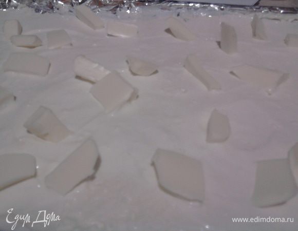 Выложить массу в форму и разровнять (масса довольно густая). Сверху смазать сметаной и разложить мелкие кусочки сливочного масла.