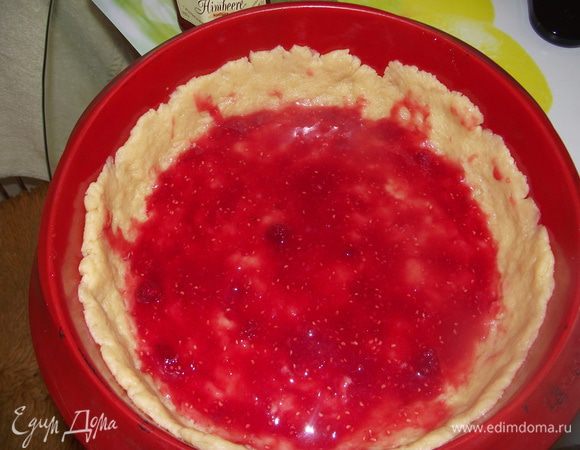 Тесто раскатайте по диаметру формы и выложите основу с бортиками. Смажьте малиновым вареньем.