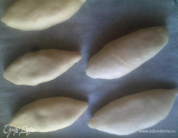 Возвращаемся к тесту, которое к этому времени подошло. Отделяем небольшой кусочек и скатываем в шарик (размером с маленькое курино яйцо). На рабочую поверхность насыпаем муку и раскатываем наш шарик в кург. Ложкой кладем в центр начинку и лепим пирожок. Кто как умеет. Я не умею никак..(( Поэтому как уж смогла, как уж инстинкт подсказал..)) Далее, таким образом творим с остальным тестом. Выкладываем на пергамент, смазываем взбитым яйцом и отправляем в духовку.