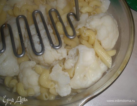 Сливаем воду, оставив примерно 1 стакан. Выкладываем пасту с капустой в форму для запекания (у меня груглая на этот раз диаметром 20 см) и немного давим капусту давилкой для пюре. 