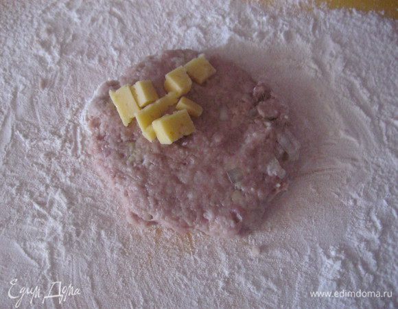 Берем немного фарша формуем шар выкладываем на рабочую поверхность уже присыпанной мукой и расплющиваем на край выкладываем сыр.