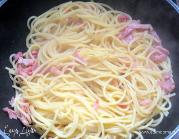 Откинуть пасту и дать хорошенько стечь воде. Перенести пасту в сковороду с грудинкой и хорошо перемешать, чтоб она впитала весь жир.
