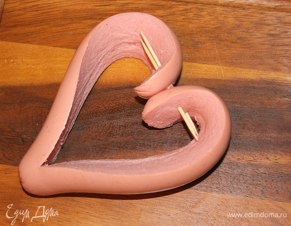 Есть 2 варианта приготовления сосисочного сердца:<br />
1) вывернуть концы сосиски наружу и соединить их с противоположной стороны, скрепив зубочисткой — получилось сердце;<br />
2) скрепить зубочисткой концы внутрь сосиски (как у меня на фото).