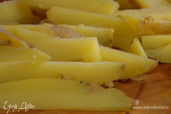 Картофель вымыть и отварить в мундире, а затем вместе с кожурой разрезать вдоль на 8 частей.