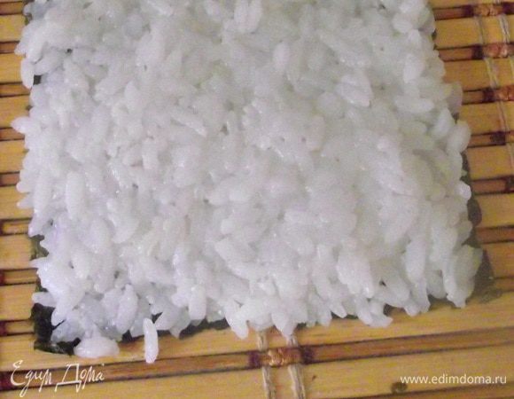 Распределить рис чуть больше половины смачивая руки в лимонной водичке, чтобы рис не прилипал.