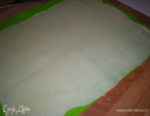 Берём первую заготовку и раскатываем максимально тонко.Я раскатываю на силиконовом коврике,это очень удобно.Не требуется подпылять поверхность мукой и можно сразу на нём выпекать или переложить с него на противень.