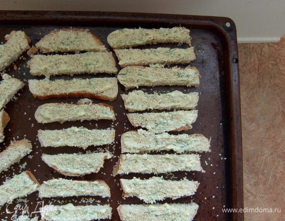 Смазать верхнюю поверхность каждого крутона маслом, присыпать кунжутом, выложить на противень. 