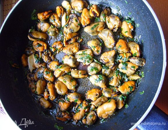 Оливковое масло прогреем, обжарим раздавленные зубчики чеснока, выложим слегка размороженные мидии, обжарим 5 мин, добавим соус, прогреем ещё пару минут, затем петрушку, перемешаем, снимем с плиты, оставим под закрытой крышкой ещё на 5 мин.