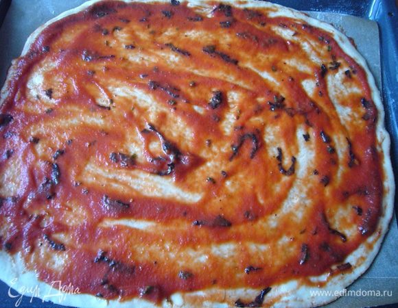 Выкладываем тесто на хорошенько подпылённую мукой поверхность и руками (кулачками) растягиваем тесто до нужного размера и формы, толщина должна быть примерно 0,3-0,5 см. Если нет времени, можно и скалкой раскатать, но при выпечке тесто не будет таким ноздреватым.
У меня в этот раз тесто было достаточно тугим, так что я его ещё и в воздухе раза 3 подбросила перед вставшими столбом изумлёнными мужчинами. Сын опомнился первым и начал кричать, что он тоже так хочет:)))
Перекладываем тесто на лист (я кладу пекарскую бумагу и присыпаю мукой), делаю лёгкий крестообразный надрез, чтобы разделить тесто на 4 сектора. Выкладываю томатный соус не доходя до края 1 см. Даём подняться тесту ещё минут 20 в тёплом месте.