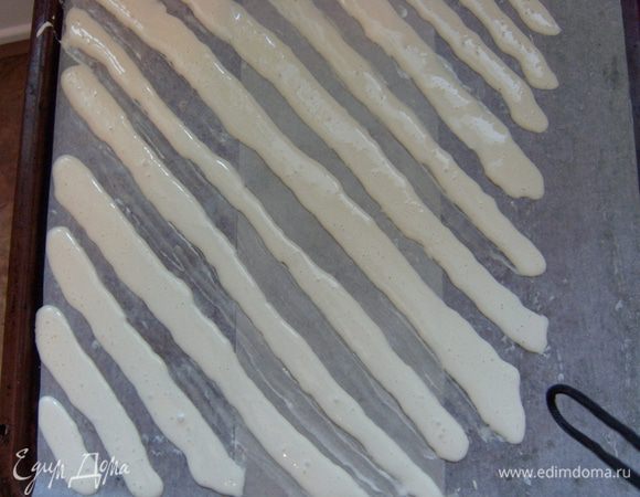 Выстелить противень пекарской бумагой, смазанной сливочным маслом. Половину получившегося белого теста положить в кондитерский мешок с обычной круглой насадкой и выложить на противень в виде диагональных полос 