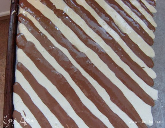 В оставшееся тесто добавить какао, тщательно перемешать. Выложить также в кондитерский мешок с аналогичной насадкой и также выложить на противень в виде диагональных полос, чередуя с белыми