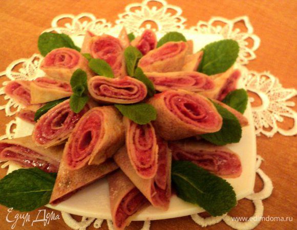 Готовые блинчики разрезать под углом, выложить на блюдо, присыпать сахарной пудрой через ситечко. Украсить листиками мяты и ягодками красной смородины. Приятного аппетита!