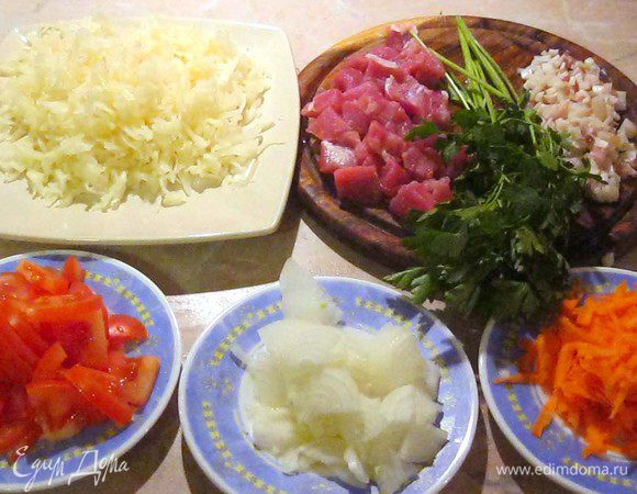 Свинину порезал небольшими кусочками. Кусочек сала, 50-70 грамм, покрошил мелким кубиком. Двести грамм капусты разложил на доске и порезал ножом вдоль и поперек, что бы она была помельче. Поскольку моркови в капусте практически нет, натер на крупной терке половину морковки. Еще нарезал одну луковицу и пару помидоров. Ну и пучок петрушки, то же не помешает.
