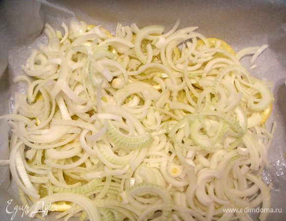 Сложить 2 листа пергамента.  Верхний лист обильно смазать оливковым маслом (1 ст.л.)  Выложить порезанный ломтиками лимон, сверху лук, порезанный полукольцами.