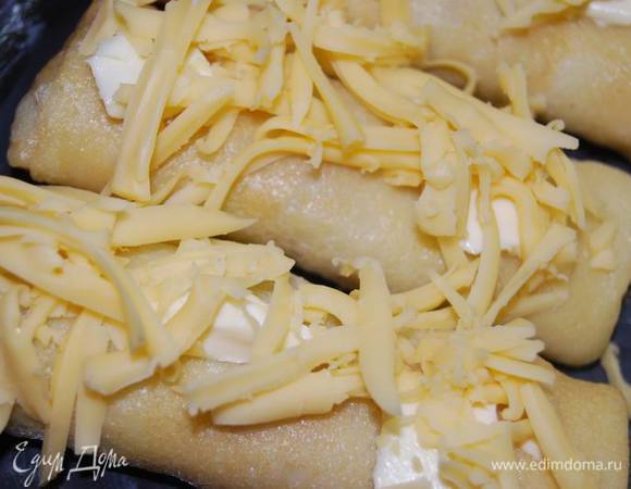 Для этого смазываем форму для запекания сливочным маслом (можно делать это в небольших керамических порционных формах),выкладываем блины. На каждый блин сверху кладем небольшой узкий кусочек масла и посыпаем тертым твердым сыром.