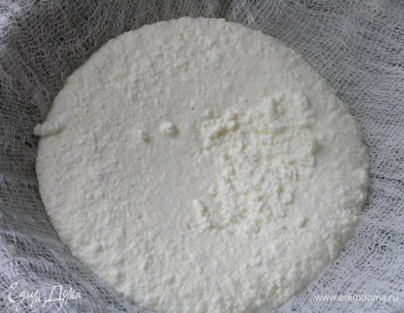 На свободную кастрюлю положить сито, застелить марлей в 2-3 слоя и выложить сваренный в молоке творог, дать стечь сыворотке.