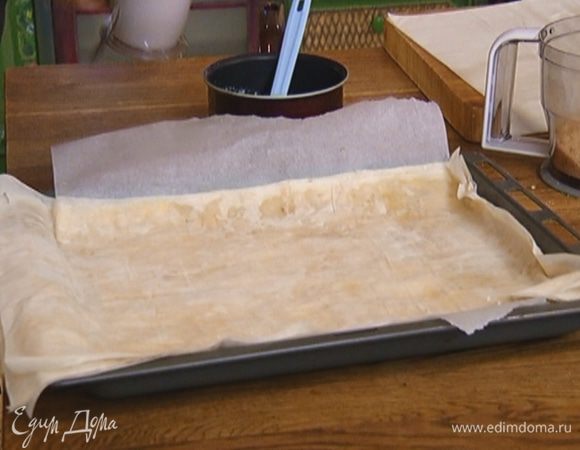 Противень выстелить бумагой для выпечки, выложить слой фило, смазать сливочным маслом и посыпать хлебно-миндальной крошкой. Уложить так же остальные слои фило — их должно быть минимум 5, максимум 10. 