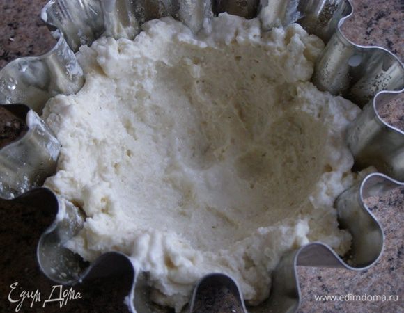 Тесто очень липкое, поэтому смочим холодной водой руки и сформуем лепешечки по размеру формочек. Аккуратно выложим тесто в формочки