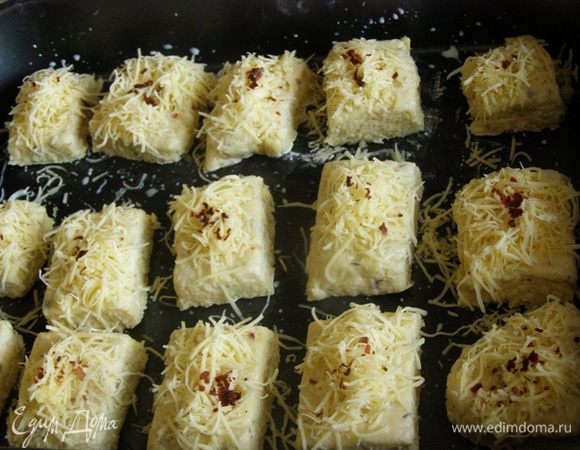 Выложим на противень, смазанный маслом, смажем молоком, посыпем тертым сыром и капелькой кайенского перца