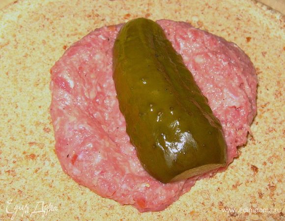Пропустить через мясорубку мясо свинины с луком и белым хлебом.Посолить, поперчить,добавить сырое яйцо и вымесить фарш.Разделить фарш на порции,сделать лепёшки и на середину положить огурчик.