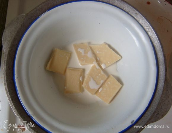 На водяной бане растопить белый шоколад в сливках, добавить сливочное масло. Остудить. Смазать получившимся кремом верхнюю часть пирога. 