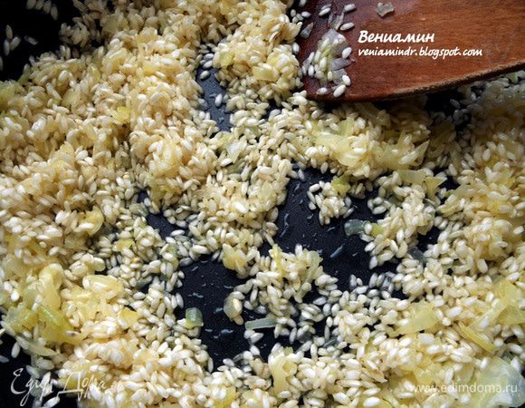 Засыпать рис, перемешать минуту, чтобы он хорошо пропитался маслом. 