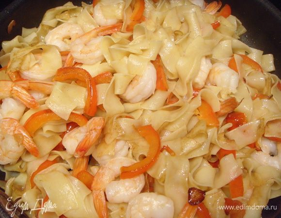 В сковороду, где обжаривался перец, выложить креветки и обжарить их 1-2 минуты. Добавить сливочного масла. Переложить лапшу. Обжаривать до образования золотистой корочки у лапши.