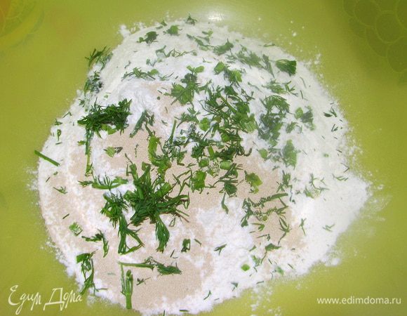 Муку просеять в большую миску, подмешать дрожжи и 1 ч.л. морской соли.Добавить рубленную зелень в муку, после чего деревянной ложкой замесить мягкой тесто, подливая оливковое масло и достаточное кол-во тёплой воды( 250-300 мл)