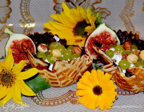 Наполняю взбитым творогом со сливками и изюмом.Сверху украшаю виноградом,грецким молотым орехом и целыми орешками фундука.Край корзиночки украшаем инжиром.