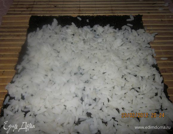 Отварить рис,добавить в него специальный уксус для суши.Лист нори разложить на циновке блестящей стороной вниз.Выложить рис.